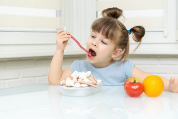 little girl makes a choice between candy and fruit. the child rejects healthy foods and chooses unhealthy foods