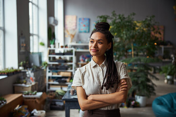 Smiling dreamy floral decorator with her arms folded looking away
