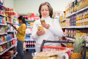 Elderly shopper using smartphone scans qr code on label in grocery supermarket