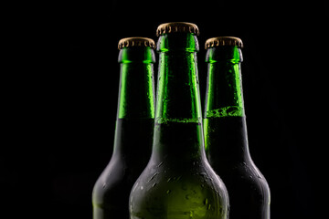 Three bottles of beer from green glass on black background.