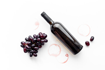 Obraz premium Red wine bottle with grapes. Top view