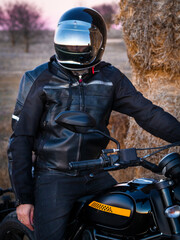 Naklejka premium Biker man with his motorcycle at sunset. Biker in the sunset light. Looking for adventure and freedom. Lifestyle photography