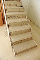 Escalones de hormigón en bruto de una escalera para forrar de madera en construcción. Reforma del...