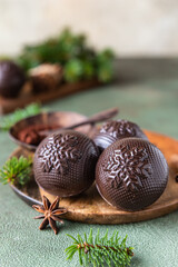 Tasty cocoa bombs with marshmallow and chocolate on wooden plate with fir branches and spices. Trendy winter hot drink.