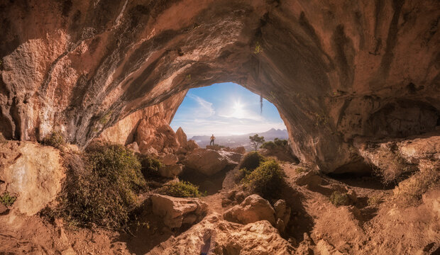 The silhouette of a man in a cave observing the beautiful views. Image of freedom. Beautiful views of Altea, Benidorm and Alicante from inside a cave. Sunset in the Sierra of Bernia

