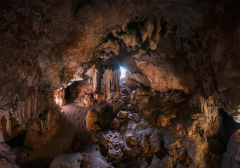 Geological formations inside a cave full of stalactites and stalagmites. Panoramic of a cave full of rock formations. The light seeps through the entrance to the cave