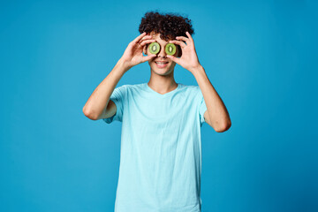 Cheerful guy curly hair kiwi near eyes isolated background