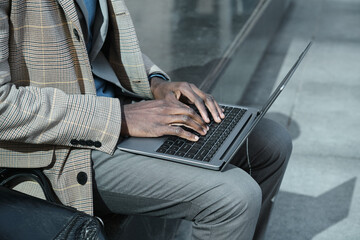 Close-up of African businessman working on laptop online outdoors