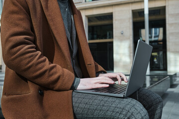 Young businessman sitting in the city and working online on laptop