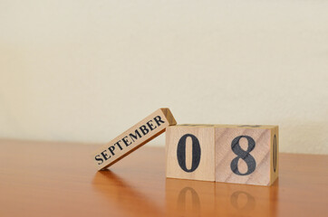 September 8, Date design with calendar cube on wooden table and white background.