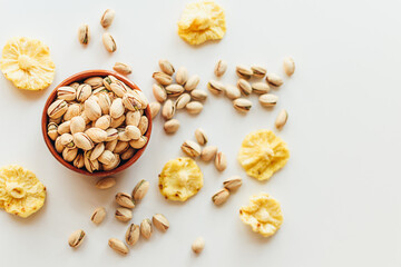 Pile of pistachios in the bowl and some dry pineapples. Healthy vegetarian protein nutritious food. Vegetarian food concept.