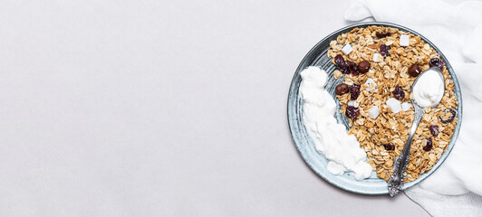 Granola with chia seeds, coconut, dry berries and yogurt in bowls on grey background, copy space. Concept of healthy breakfast menu