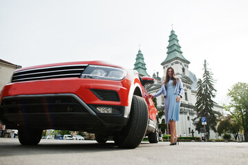 Outdoor photo of gorgeous woman posing near orange suv car.