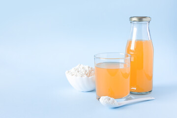 Protein or collagen and orange juice on a blue background. Food supplement concept. Natural beauty and health supplement. Plant based collagen. Copy space.
