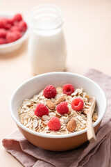Dry oats, oat muesli with raspberries and almond nuts in a bowl. Healthy nutritious breakfast food. Dieting, weight loss concept