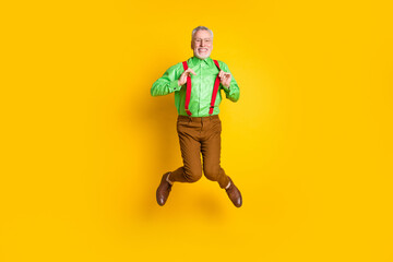 Full size photo of aged man happy positive smile have fun jump up isolated over yellow color background