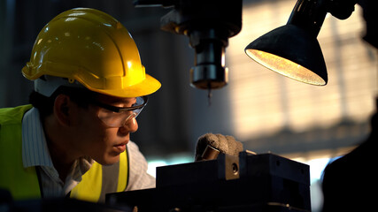 asian worker wearing helmet and safety glasses working  with machine in factory . industrial...