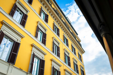 Low angle shot showing details of European classic building with beautiful Italian architectural style window panels located on street of Rome in Italy