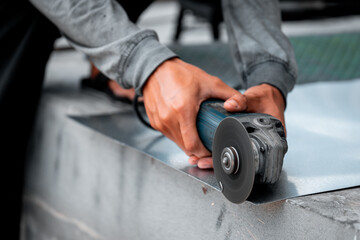 Hand grinder, male worker cutting with a small iron cutter. The cutting zinc plate