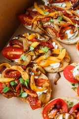 
A set of different snacks for a party or a festive table. Ciabatta sandwiches with tomatoes, jamon, cream cheese, vegetables, chambers and olives. Delicious wine snacks