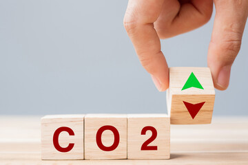 hand flipping wooden cube blocks to UP and Down arrow symbol with CO2 (Carbon dioxide) text on...