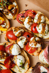 
A set of different snacks for a party or a festive table. Ciabatta sandwiches with tomatoes, jamon, cream cheese, vegetables, chambers and olives. Delicious wine snacks