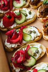 
A set of different snacks for a party or a festive table. Ciabatta sandwiches with tomatoes, jamon, cream cheese, vegetables, chambers and olives. Delicious wine snacks