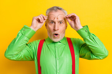 Photo of impressed aged grey hairdo man hold eyewear wear green shirt isolated on yellow color...