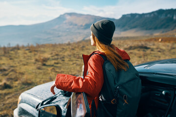 woman travels in nature with a backpack and near the car - obrazy, fototapety, plakaty