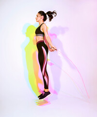 Happy attractive woman doing stretching exercise or youga moves with glitch duotone effect. Young sporty model at studio and double colorful shadows