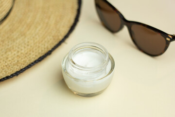 Obraz na płótnie Canvas Closeup of a jar of moisturiser, straw hat and sunglasses. Concept of skin care for summer.
