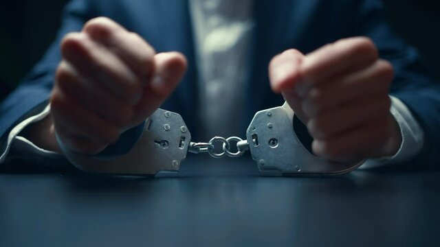 Arrested criminal businessman in handcuffs in the interrogation room. Arrest of the offender. Detention and interrogation of the accused man.