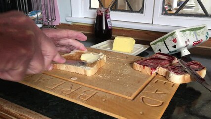 Toast having butter and cherry jam spread on it in the kitchen of an Oakham dwelling place in the county of Rutland in England, United Kingdom.