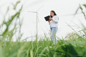women engineer working and holding the report at wind turbine farm Power Generator Station on...