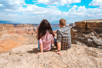 A young couple, a man and a woman, embrace on the edge of a canyon and enjoy the view of Alstrom point, Utah, USA