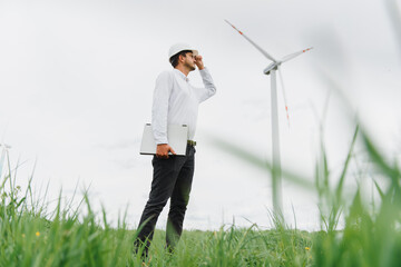 Engineer worker with laptop or computer at wind turbine power station construction site,copy space.