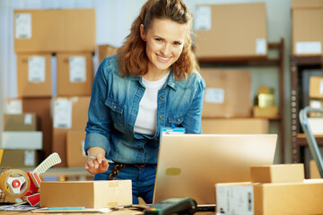 happy young female in jeans with laptop in warehouse