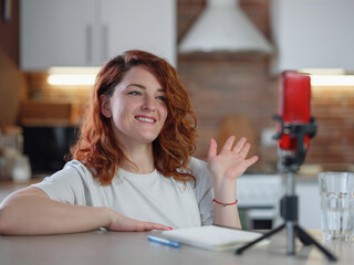 Technology and blogging concept. Redhair woman recording video concent for her blog at home