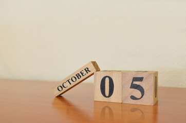 October 5, Date design with calendar cube on wooden table and white background.