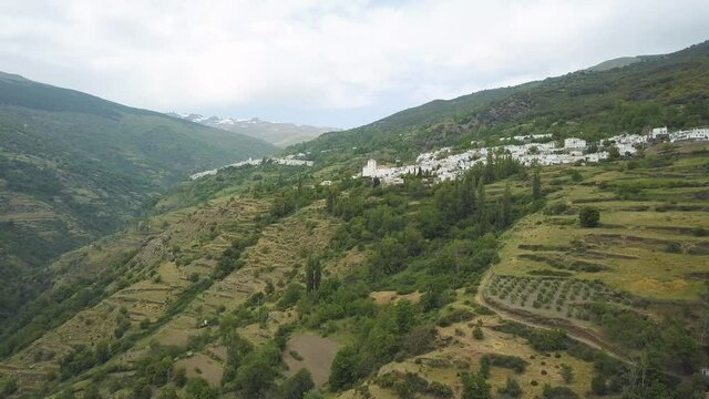 Aerial ascending view of the valley of Poqueira with the villages of Bubion and Capileira with Sierra Nevada behind. Las Alpujarras.