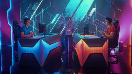 Two Professional Esport Gamers Using Controllers Playing Console Video Games on a Championship Event with Big TV Screens and Stylish Neon Arena. Global Online Streaming Cyber Gaming Tournament © Gorodenkoff