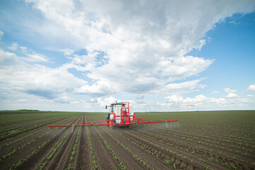 Tractor spraying pesticides at corn fields