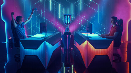 Two Professional Esport Gamers Using Controllers Playing Console Video Games on a Championship Event, One Player Celebrates Victory with Raised Hands. Global Online Streaming Cyber Gaming Tournament © Gorodenkoff