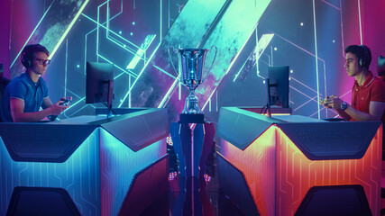 Two Professional Esport Gamers Using Controllers Playing Console Video Games on a Championship Event with Big TV Screens and Stylish Neon Arena. Global Online Streaming Cyber Gaming Tournament © Gorodenkoff