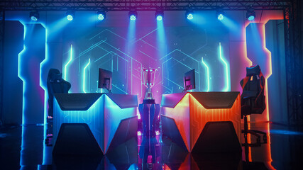 Two Person Empty Computer Gaming eSports Championship Arena with Winner Trophy Standing on a Stage. Stylish Online Live Streaming Tournament with Big Screens Showing Graphics and Neon Stage © Gorodenkoff