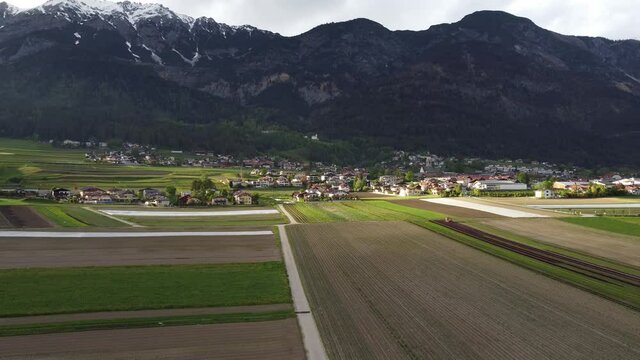 Farmlands in valley in Alps mountains. Village Thaur in Austria, Tyrol. Tyrolean village during sunset.