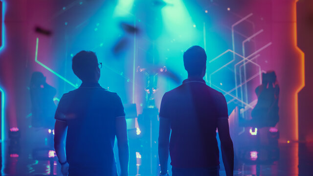 Two Professional eSports Gamers walking on Stage to Participate in the Cyber Games Championship Event. Competitive Online Live Streaming Tournament. Stylish Back View Shot