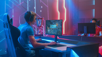 Professional eSports Gamer Plays Mock-up 3D First Person Shooter Video Game His Personal Computer, Celebrates Winning of the Round. Cyber Gaming Tournament / Championship. Side View Shot © Gorodenkoff
