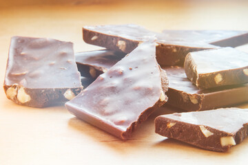 Homemade chocolate bars with nuts in soft focus at high magnification. Background with broken craft chocolate bars
