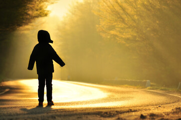 Silhouette of boy looking at sun rays.